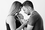 Eltern mit Baby auf dem Arm - Stirn am Stirn